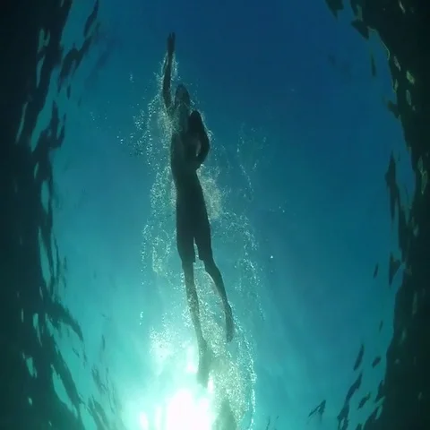 UNDERWATER LOW ANGLE: Athletic man swimming crawl in blue ocean on sunny day Vidéo 69461468