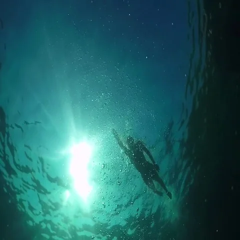 UNDERWATER LOW ANGLE: Young man swimming front crawl in blue sea on sunny day Stock Footage 69461794