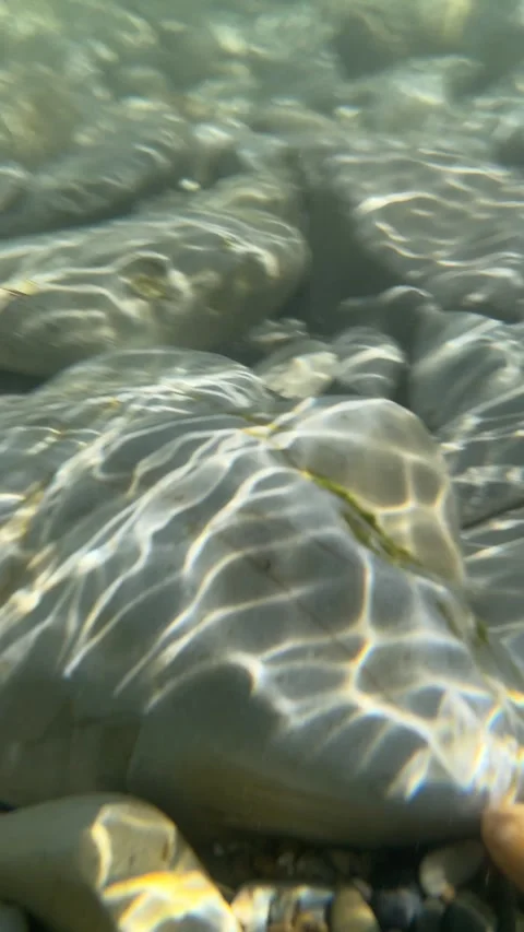 Underwater movement of waves over smooth stones Video stock 283485816