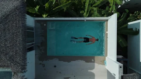 Underwater rooftop pool shot: man glide beneath water surface against villa Stock Footage 312744046