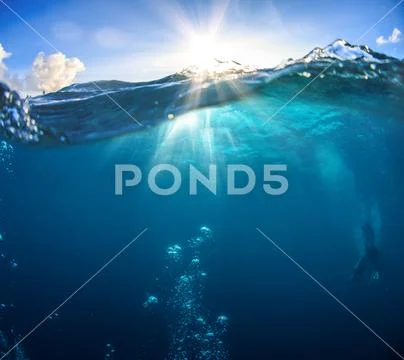 Underwater scenery, deep blue water of the ocean, air bubbles, waterline spli Stock Photos