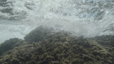 Underwater sea waves break into the rock and form bubbles in slow motion Stock Footage 108278912