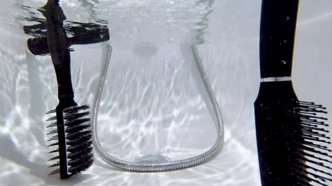 Underwater shooting. Various combs fall into a bath of water. Video stock 130662404