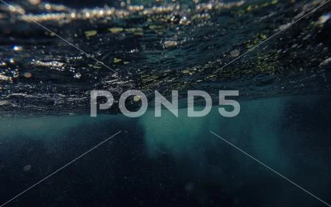 Underwater shot of blue ocean water, air bubbles, sunbeams on water surface Stock Photos