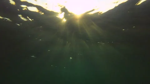 Underwater shot, Red rays of the setting sun penetrate the surface of the water. Stock Footage 230508549