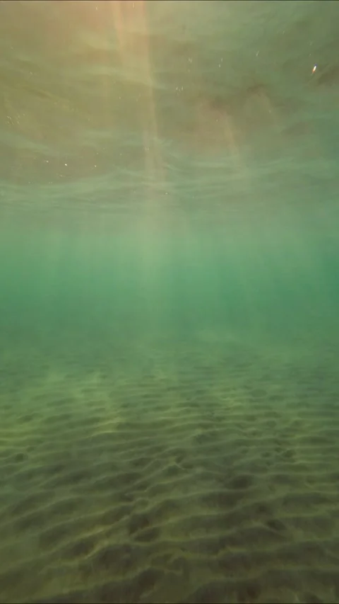 Underwater shot, Sunrays above sandy bottom of the setting sun penetrate the sur Stock Footage 232767204
