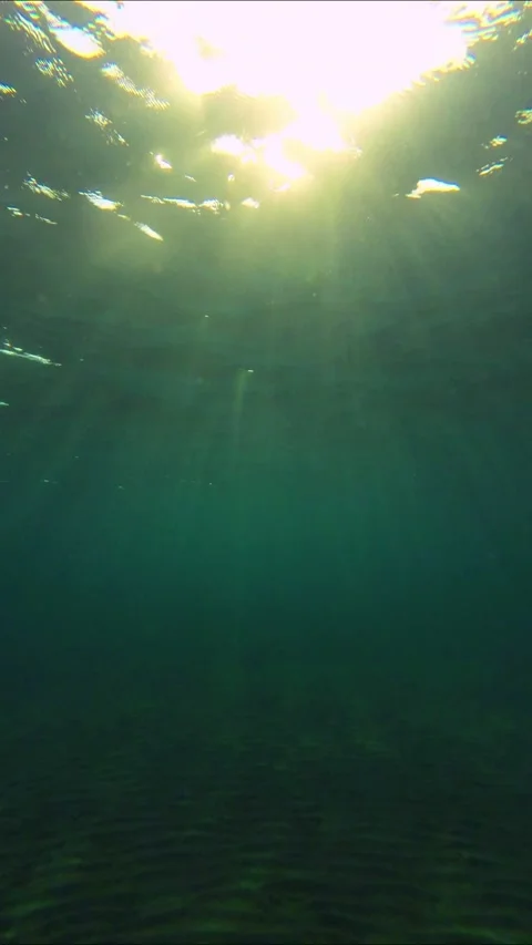 Underwater shot, Sunrays of the setting sun penetrate the surface of the water.  Video stock 232767245