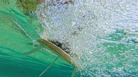 UNDERWATER, SLOW MOTION, CLOSE UP: Surfboard glides across crystal sea water Video stock 313761426
