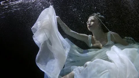 Underwater slow motion shot of floating woman inside dark river 스톡 동영상 167279153
