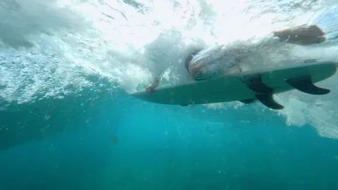 UNDERWATER SLOW MOTION Unrecognizable surfer paddling in blue ocean on surfboard Stock Footage 85649430