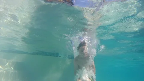 Underwater slow motion of young boy doing a cannonball into pool Stock-Footage 99313102