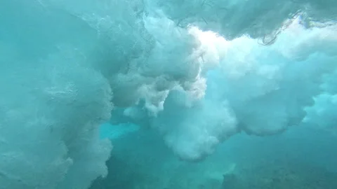 UNDERWATER: Sunlight filters through cloud of foam as wave breaks above reef Stock Footage 339080074
