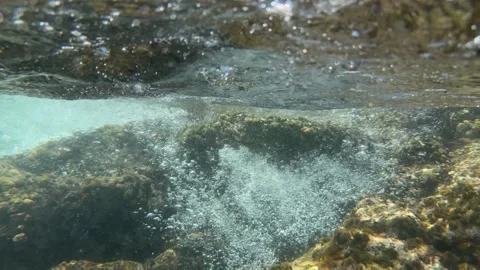 Underwater tidal wave moves above rocks creating rising air bubbles beneath the Stock Footage 342335868