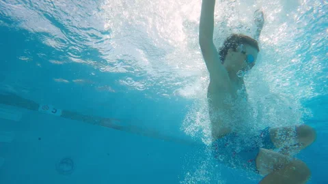 Underwater view of 10 year old boy jumping into pool with copy space Vidéo 248081455