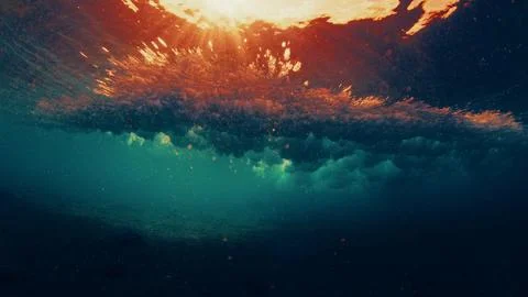 Underwater view of a breaking ocean wave with golden sunset light reflecting Stock Photos