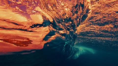 Underwater view of a breaking ocean wave with golden sunset light reflecting Stock Photos