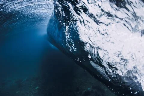 Underwater view inside breaking ocean wave, blue water tunnel with light rays Stock Photos
