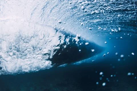Underwater view inside a breaking ocean wave, blue water with light rays Stock Photos