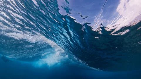 Underwater view inside a breaking ocean wave, forming a blue barrel with white Stock Photos