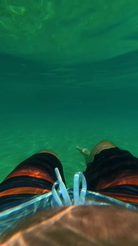 Underwater view, legs in swim trunks. Trani Ammouda, Greece. Vertical Stock Footage 338358059