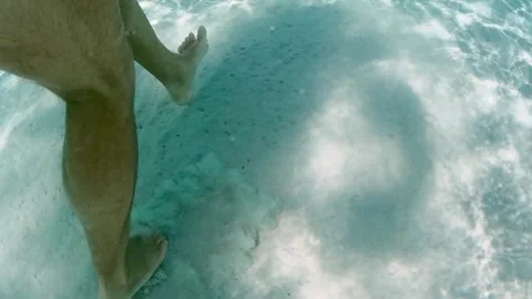 Underwater view of legs walking on sandy sea floor with sunlight Video stock 278952332