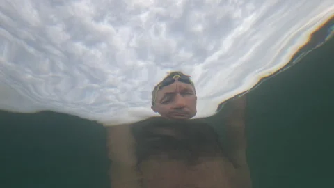 Underwater view looking up at a swimmer's silhouette distorted by the rippling Stock Footage 344830406
