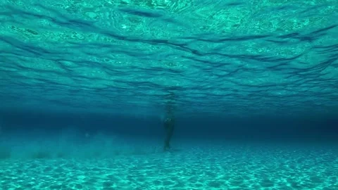 Underwater view of man walking on sandy sea floor Stock Footage 278952444