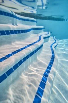 Underwater View of Pool Steps with Blue Tile and Sunlight Reflections in Clear 写真素材
