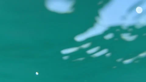Underwater view of rippling water surface with bright sunlight and glimpses of s Stock Footage 338001930