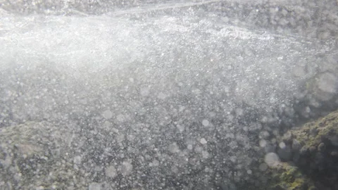 Underwater view showing bubbles creating turbulence, with sunlight piercing the Stock Footage 343195283