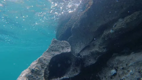 Underwater view of waves crashing into a large rock Stock Footage 228624519
