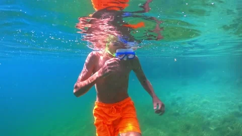 Underwater view of young boy with diving mask and orange swim trunks floati.. Stock Footage 321195602