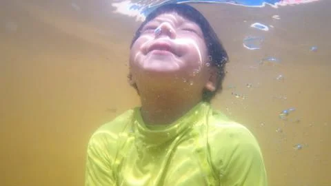 Underwater view of young boy diving into a murky thermal pool water Stock Photos