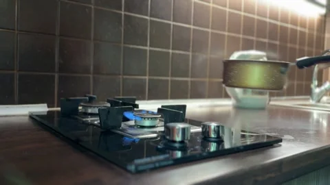 Uneven gas flame under pan adjusted with metal utensil Stock-Footage 310502380