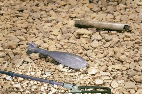 An unexploded mortar mine lying on the rocks. Clearance of unexploded shells  Stock Photos