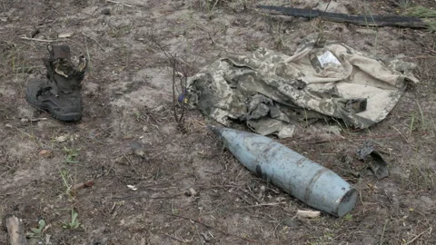 Unexploded shells on the ground and military uniform Stock Footage 195806130