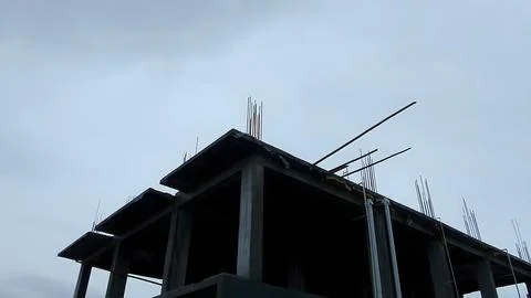 Unfinished concrete building framework under cloudy sky with concrete Stock Photos