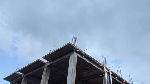 Unfinished concrete building structure under construction against cloudy sky Video stock 343553326