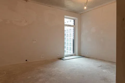 Unfinished empty room with bare plaster walls, concrete floor and single ha.. Foto stock