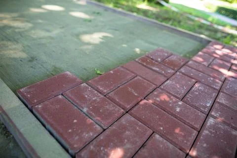 Unfinished pedestrian walkway made of rectangular red paving stones. Stock Photos