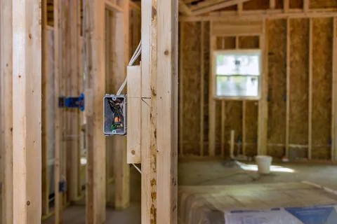 An unfinished wood frame house with basic electrical wiring is being constructed 스톡 사진