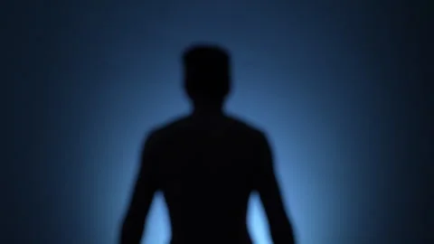 Unfocused backlit man slowly walking towards a white light Stock Footage 278239183