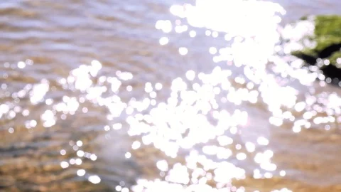 Unfocused sun reflection flares from ocean water with waves coming slow motion Stock-Footage 99136749