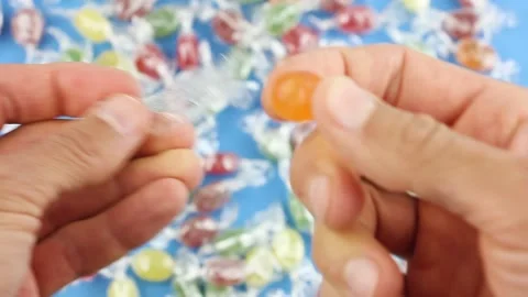 Unfold orange candy on background of many colored candies, sugar sweets Stock-Footage 156474697