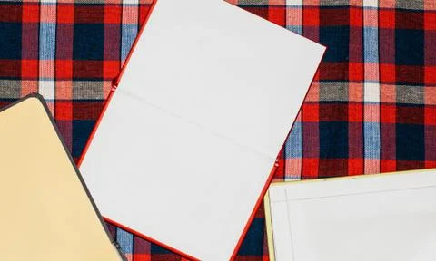 Unfolded notebooks with white sheets on a colored background in a cell Stock Photos