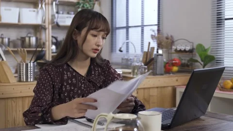 Unhappy asian lady comparing data on the paper Stock Footage 160822473