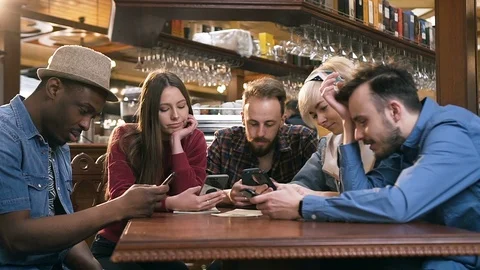 Unhappy, boring group of friends using smart phone during resting in the pub Stock Footage