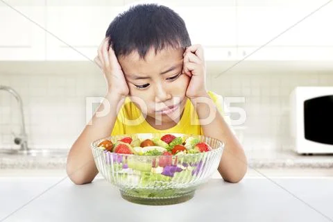 Unhappy child to eat salad Stock Photos