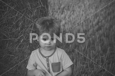 Unhappy child at hay bale, summer Stock Photos