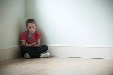 Unhappy Child Sitting In Corner Of Room Stock Photos